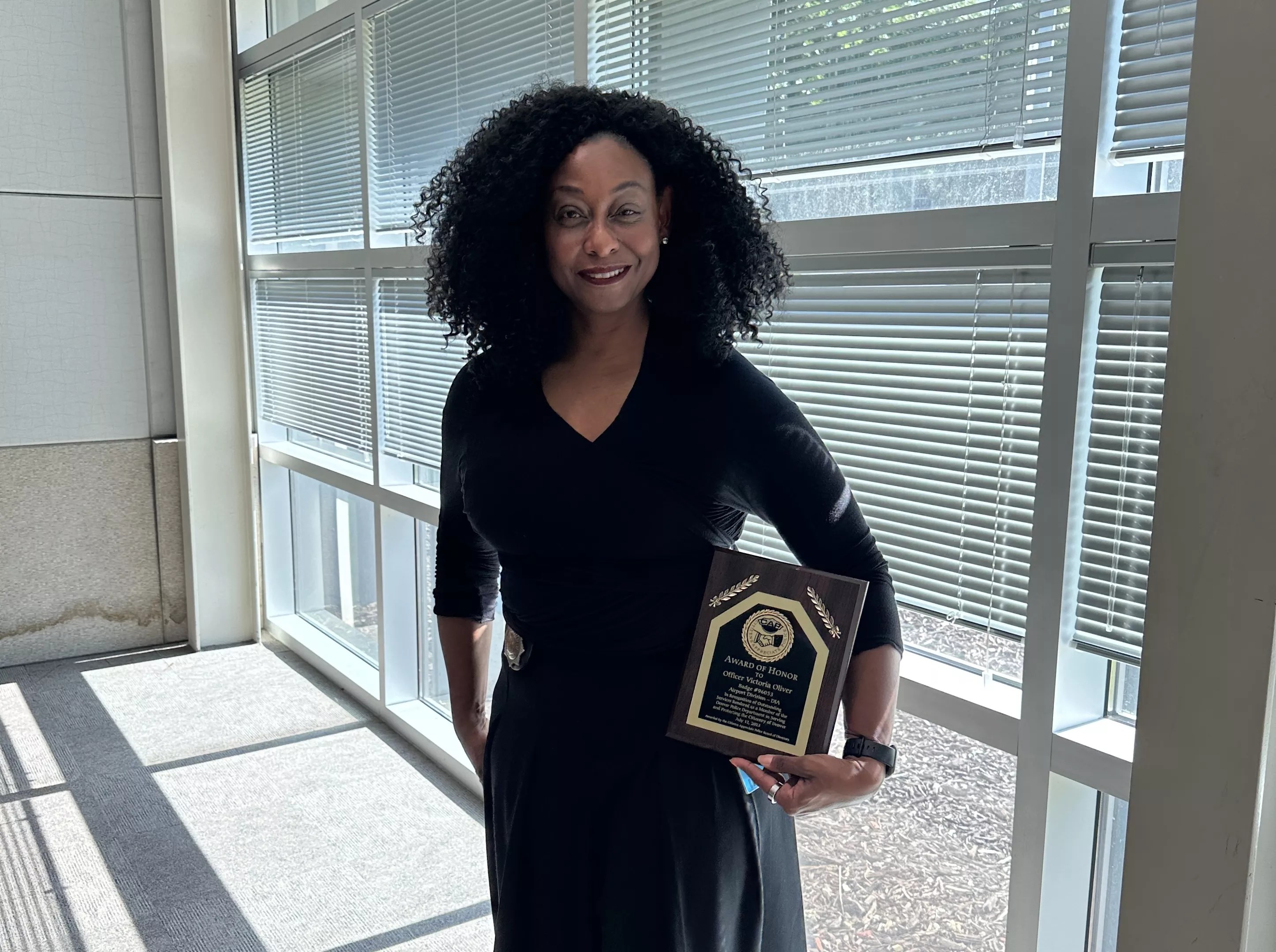 Officer Victoria Oliver standing with her Citizens Appreciate Police (CAP) award that she received for buying a plane ticket for a woman to escape domestic violence.