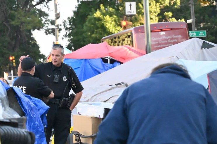 Denver Police officers talk at the corner of 8th Avenue and Logan Street.