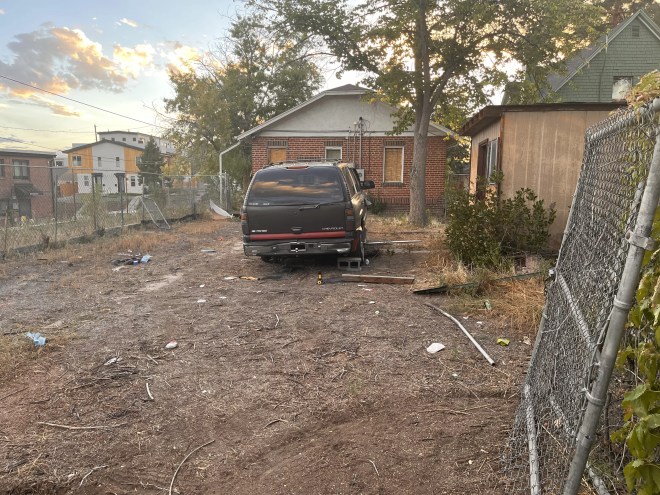 A black SUV sits behind a red-brick home.