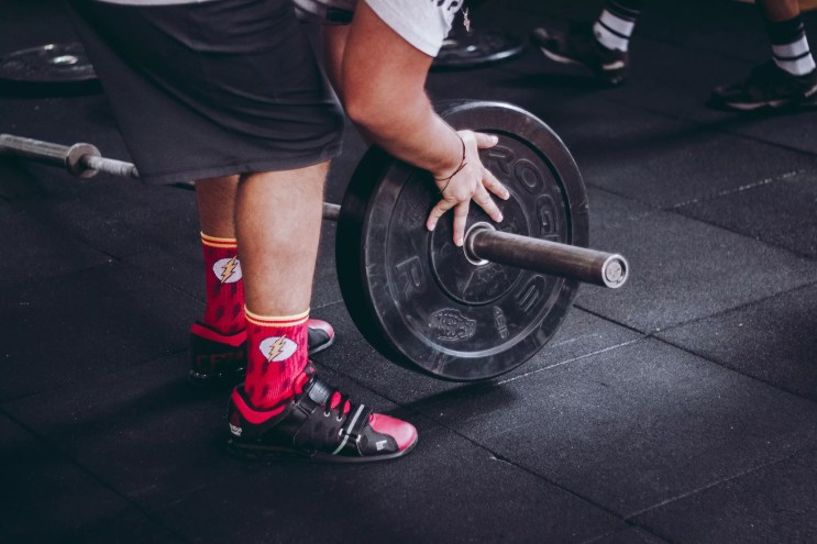 A man puts weights on the dead lift bar