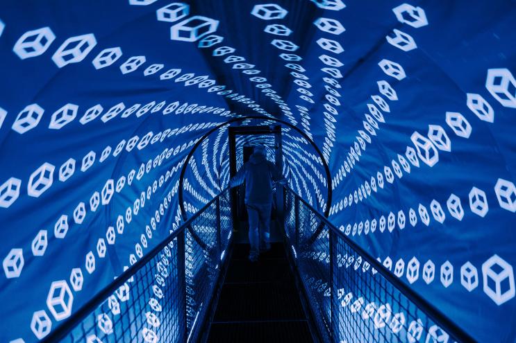 blue lights cover a tunnel-shaped room with a bridge in the center