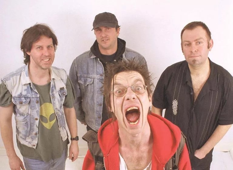 punk musicians posing for a photo against a pale pink background