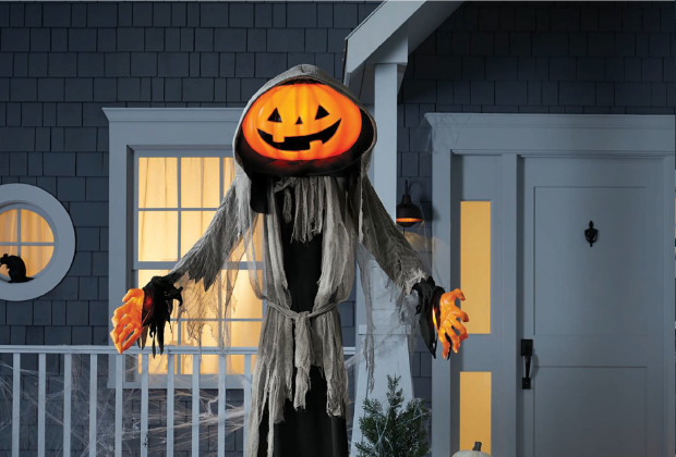 ghoul with pumpkin head in front of house