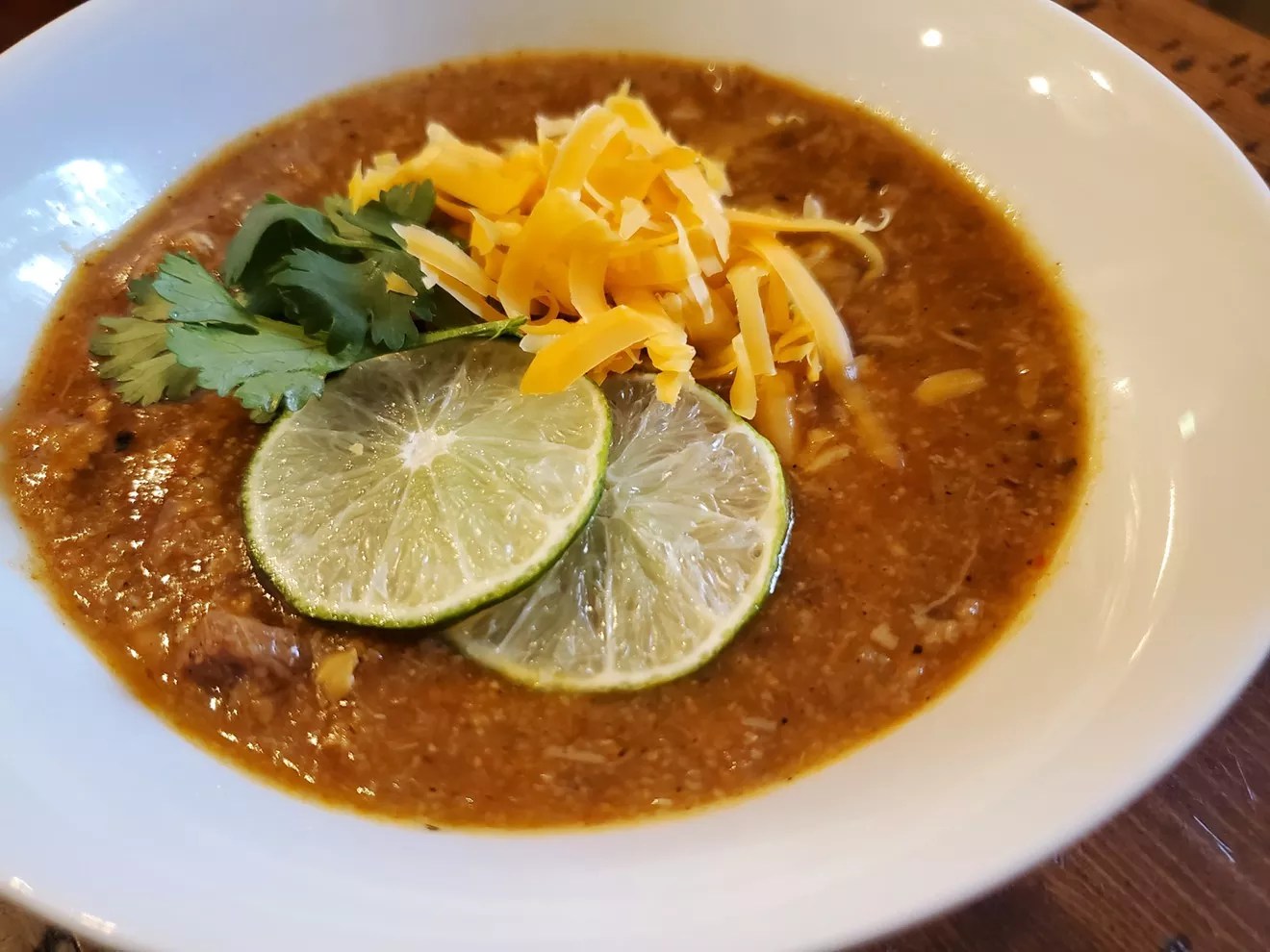 bowl of green chile with lime, cheese