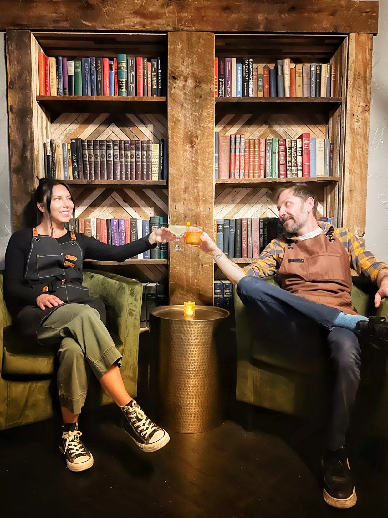 two people sitting in chairs in front of a bookcase