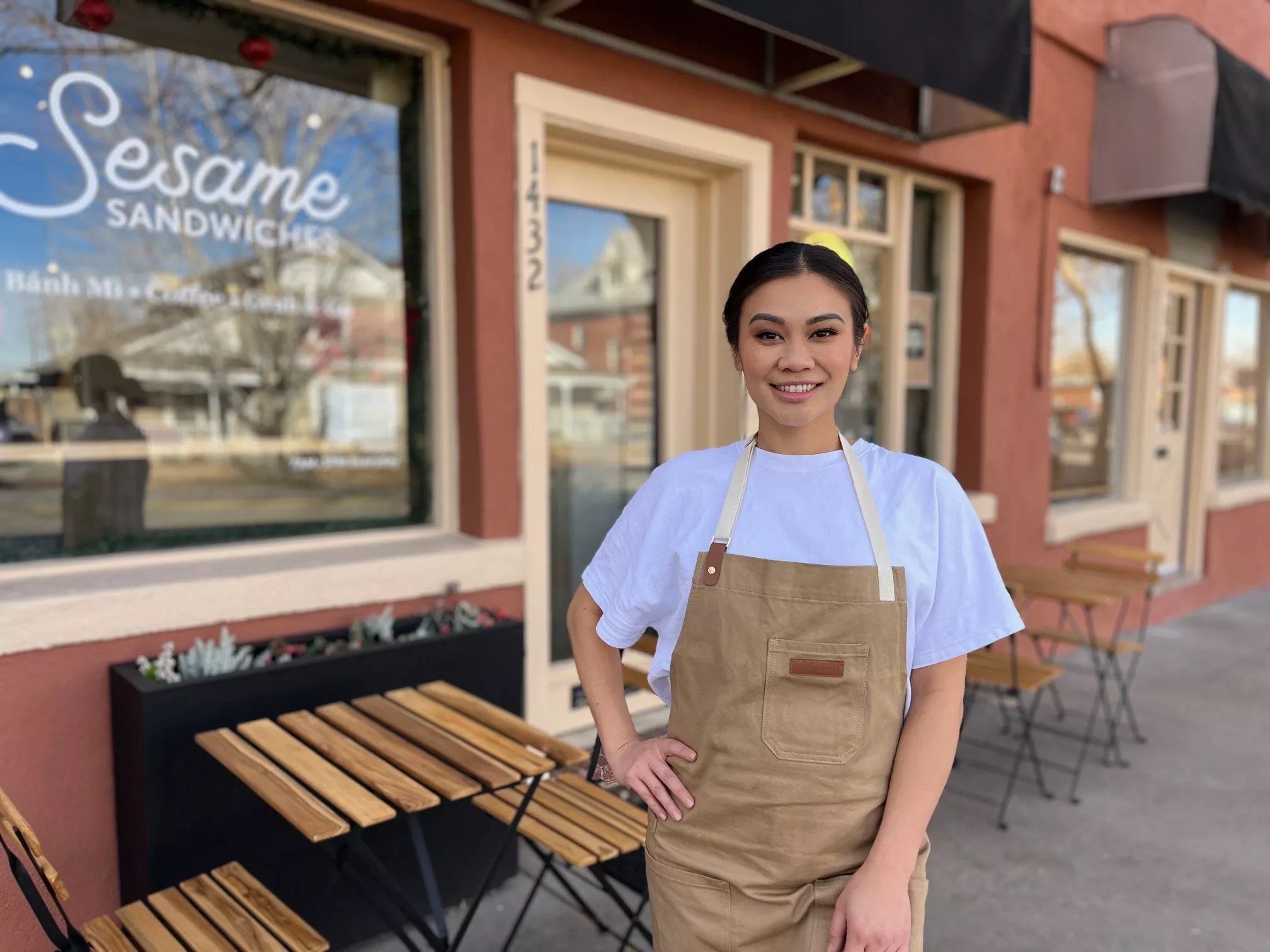 woman standing in front of a storefront in an apron