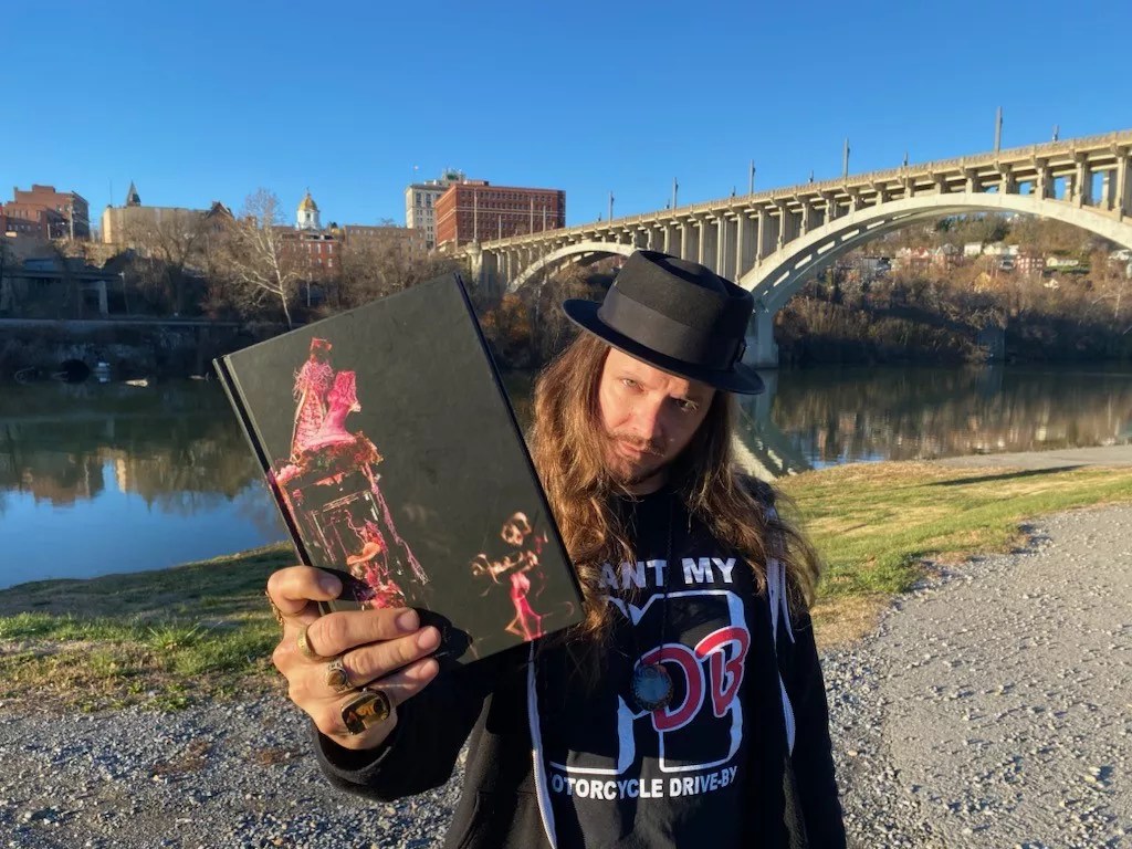 man holding a copy of a book outside