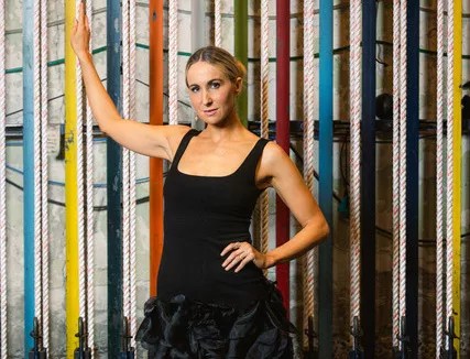 comedian nikki glaser leaning on a wall