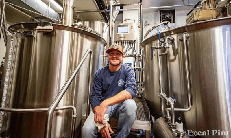 a man in front of brewing equipment