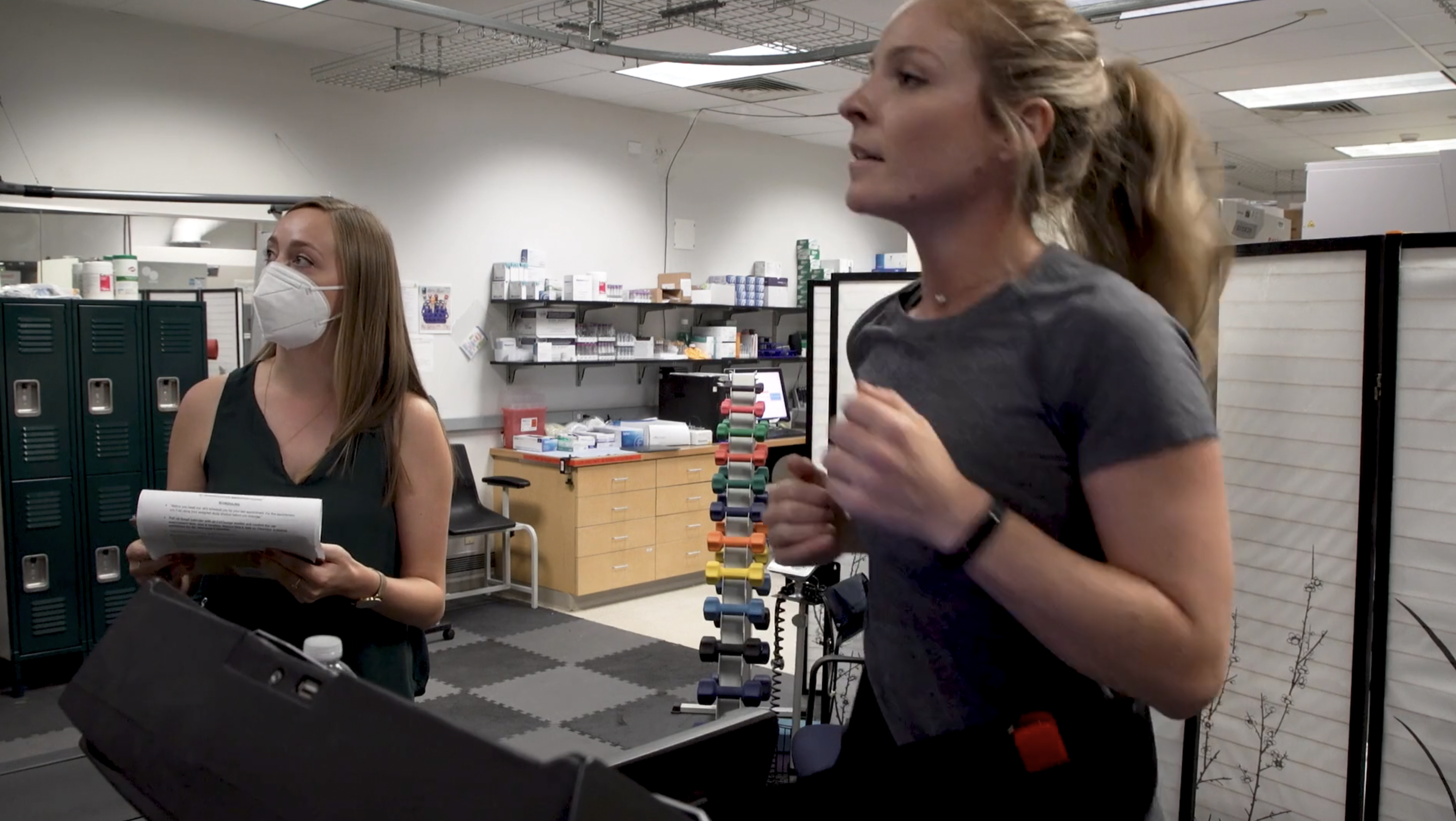 Woman runs on a treadmill while a woman takes notes