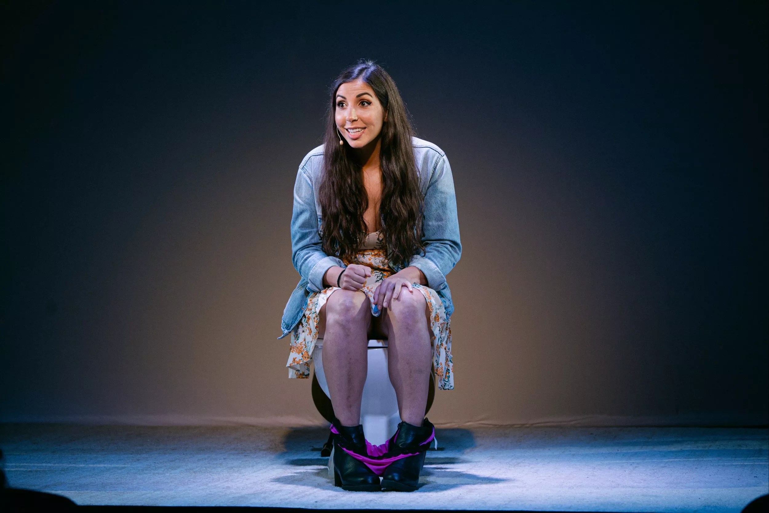 woman on stage sitting on toilet