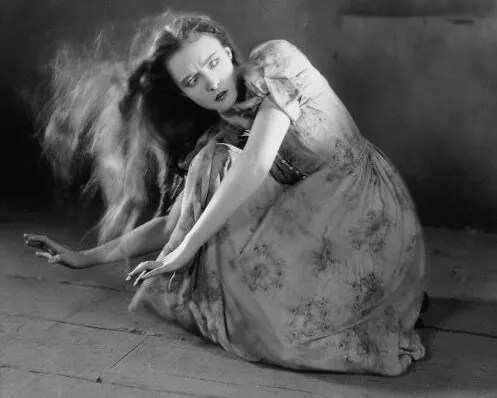 woman in prairie clothes caught in wind crouched on the ground