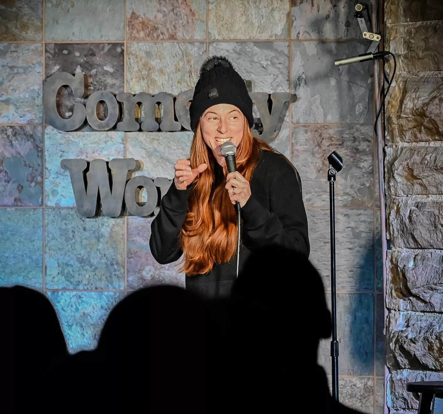 red haired woman in beanie at a microphone