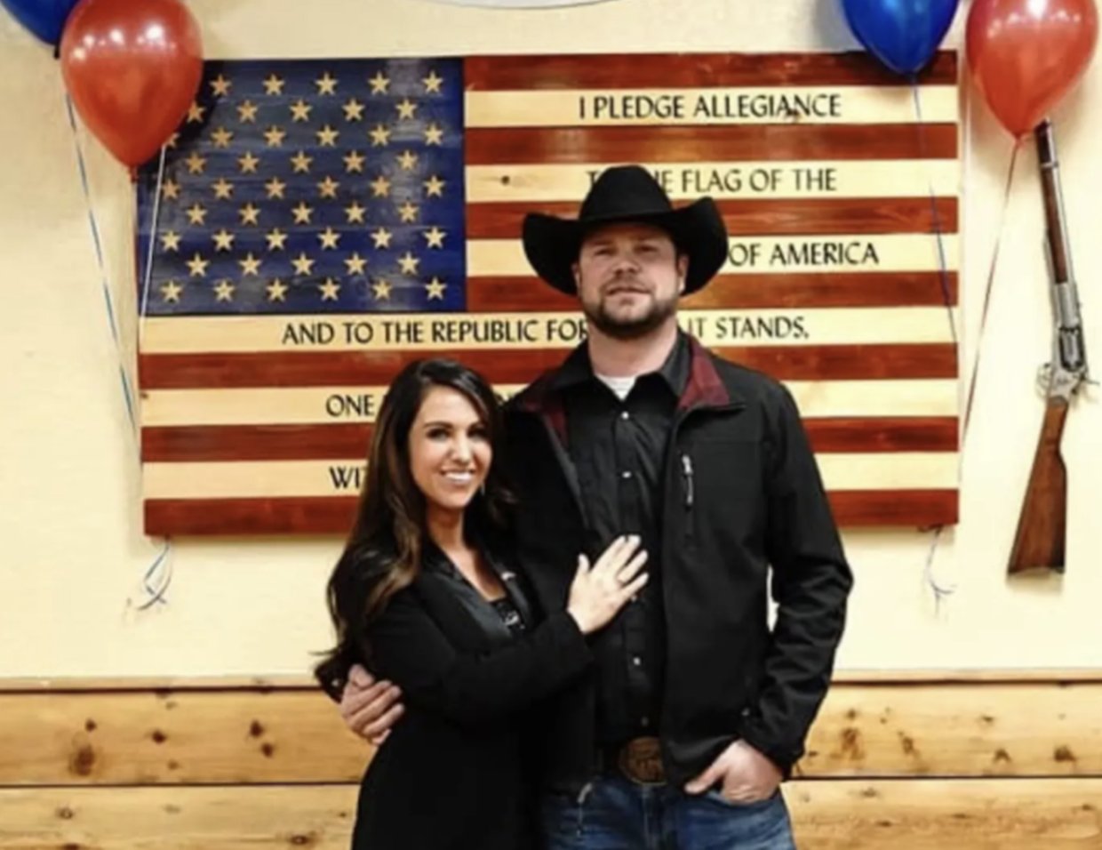woman and man in cowboy hat in front of flag.