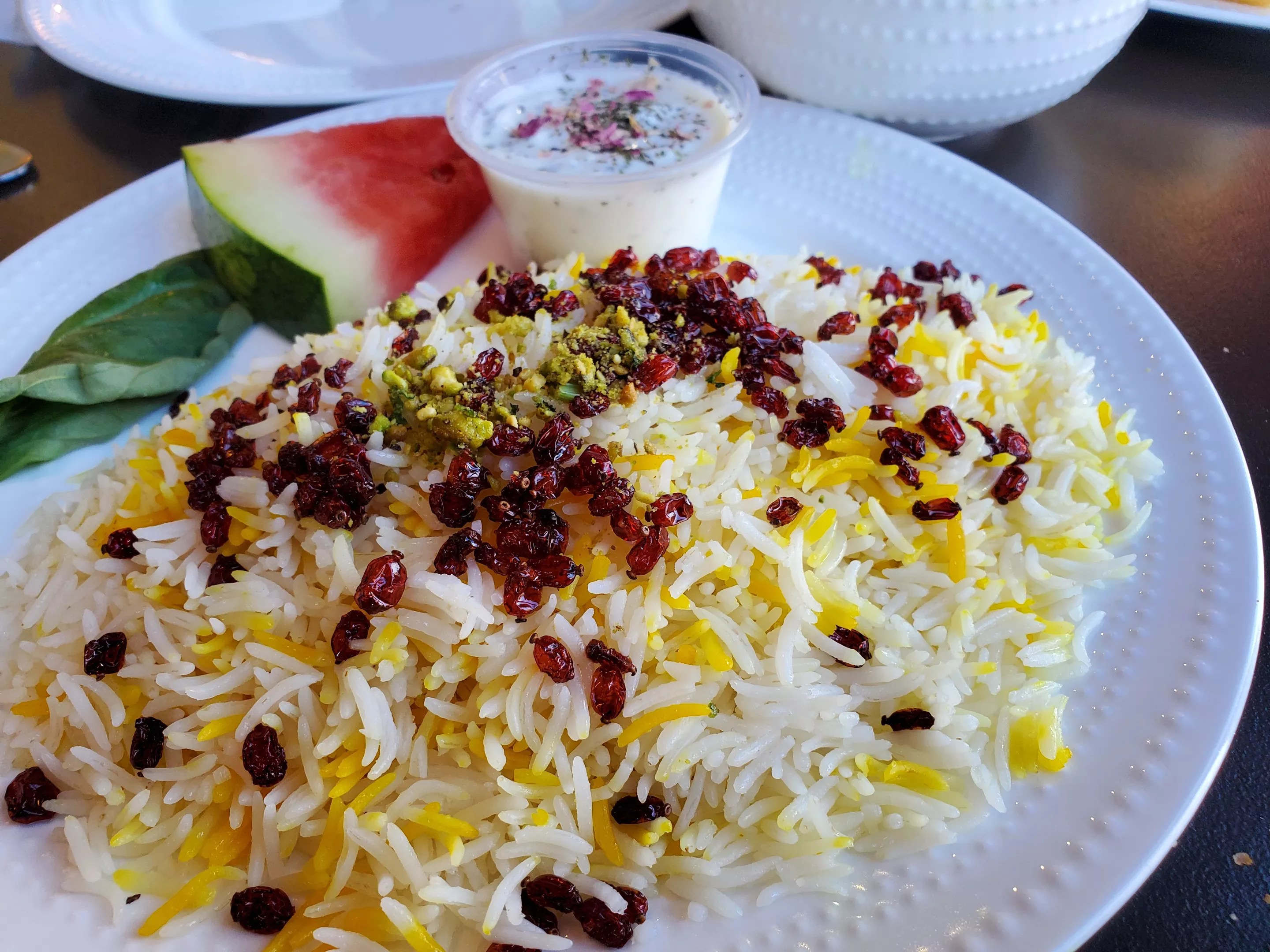 a plate of rice topped with barberries and pistachios.