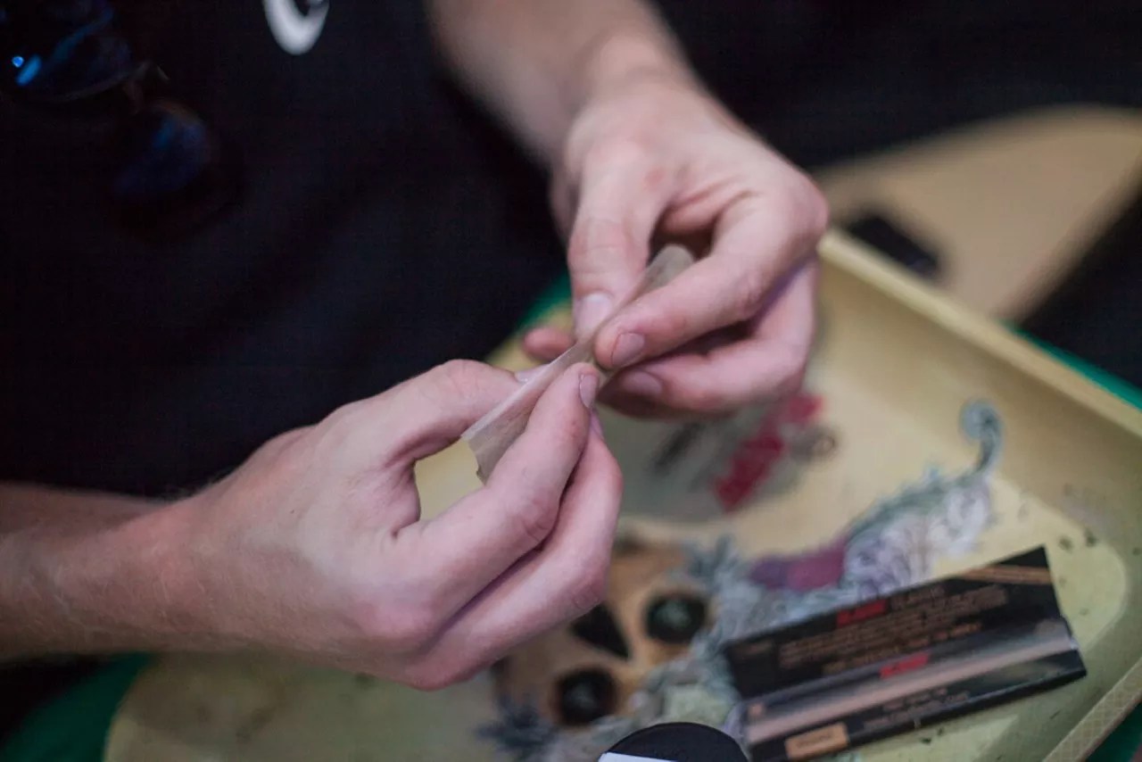 Hands roll a marijuana joint over a RAW tray