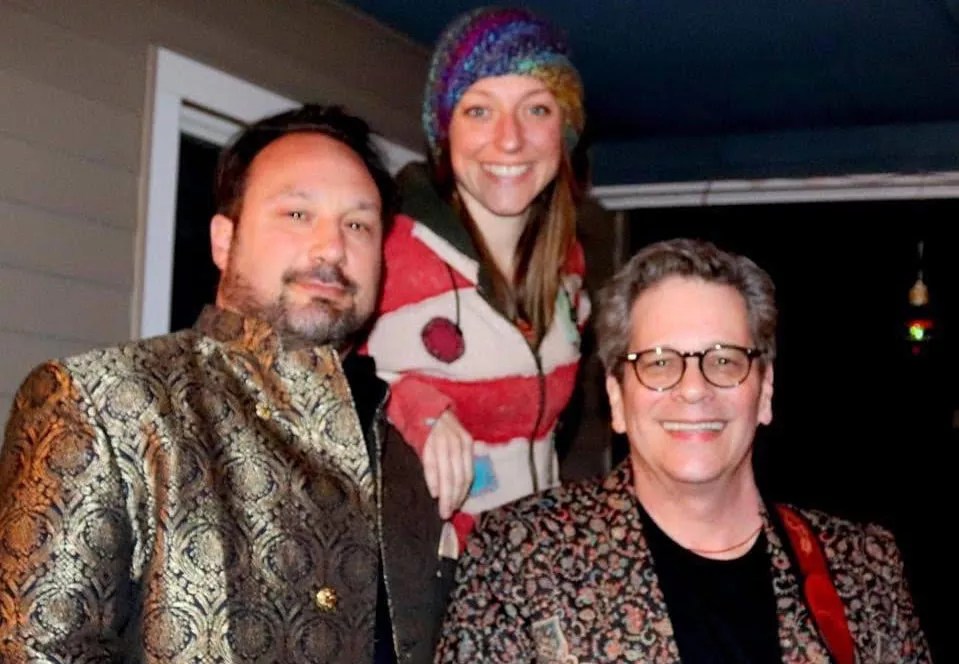 two men and a woman smile for the camera