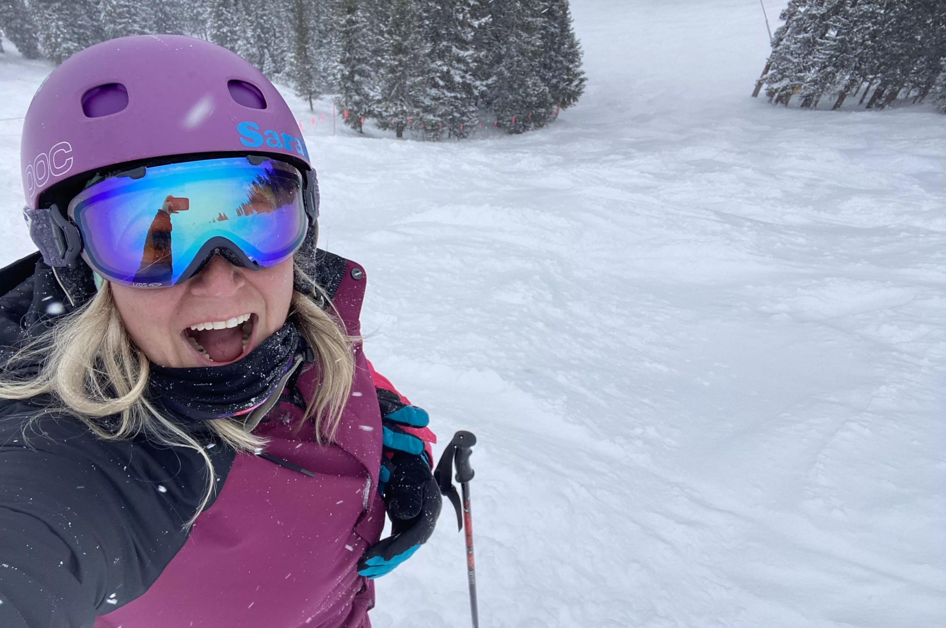 A woman in pink jacket takes selfie while skiing in snow