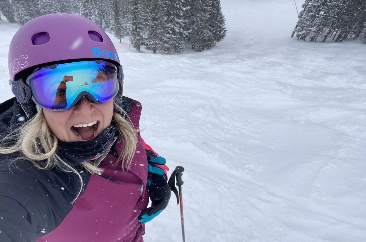 A woman in pink jacket takes selfie while skiing in snow