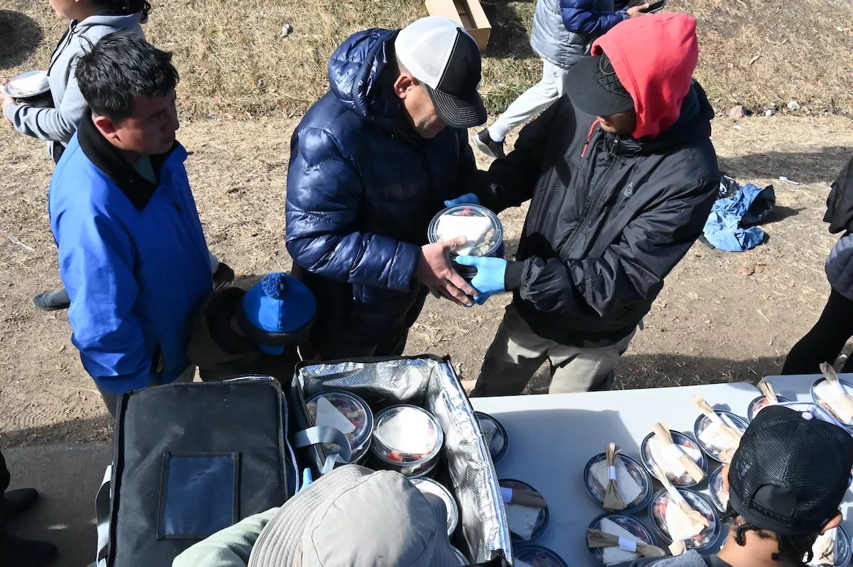 Migrants pick up a lunch in Denver.