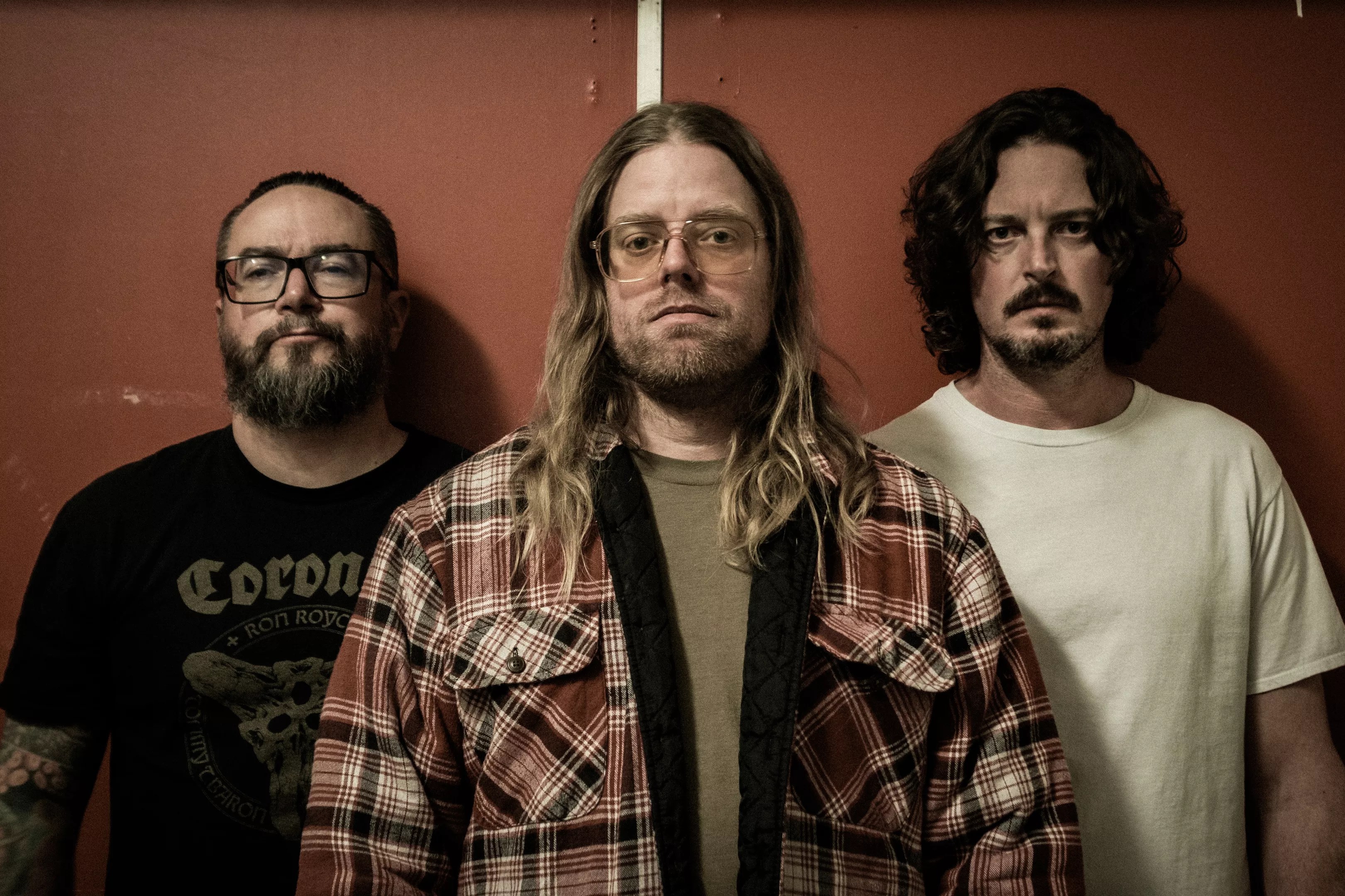 three metal bandmembers pose for a photo.