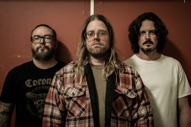 three metal bandmembers pose for a photo.