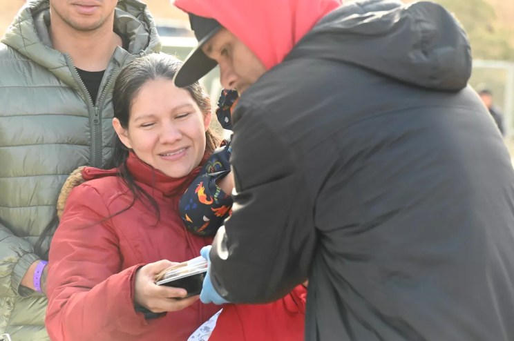 A migrant takes a packaged meal from SAME Cafe.