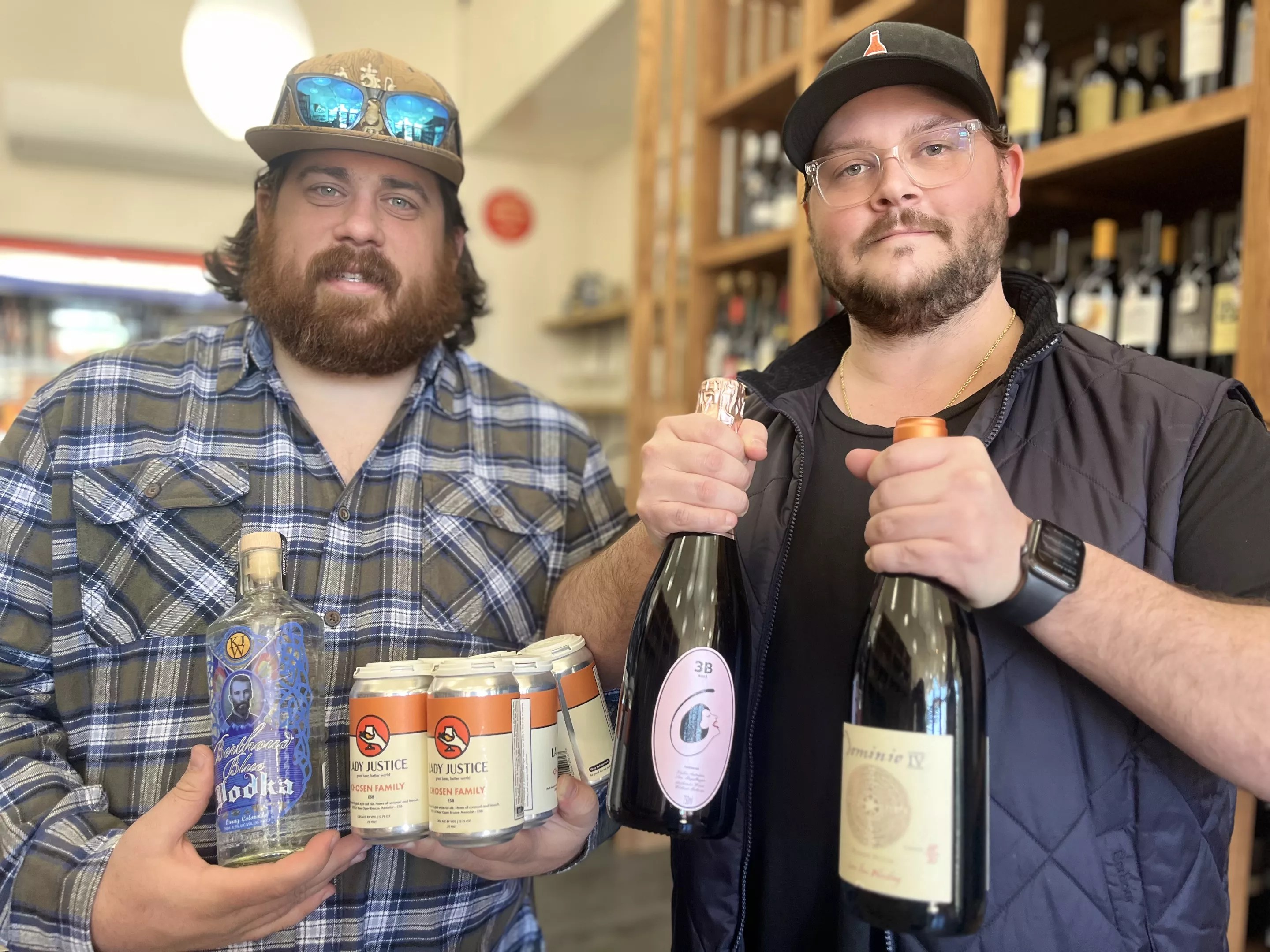 two men holding bottles of wine and cans of beer