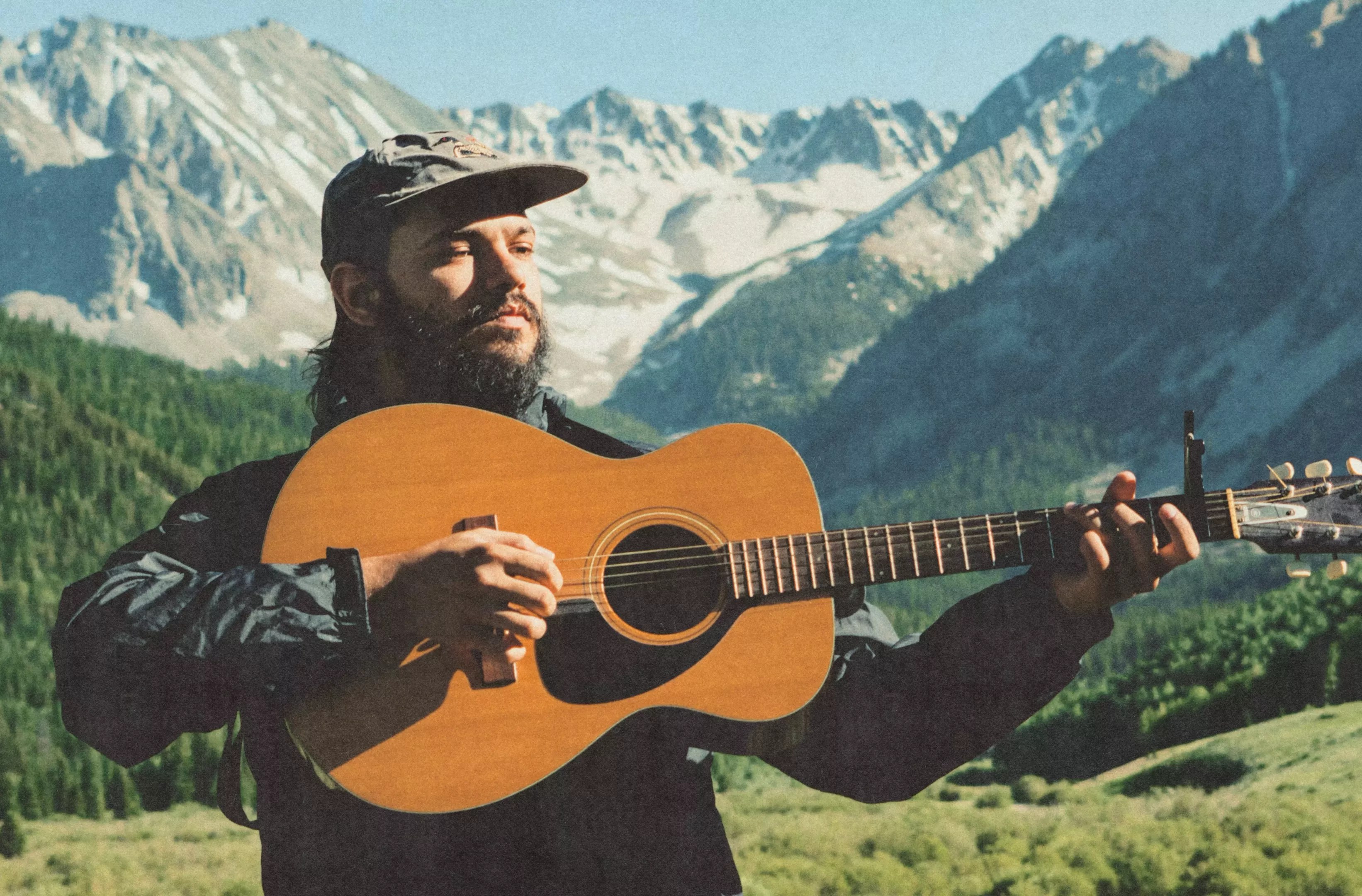 man holding acoustic guitar in the mountains