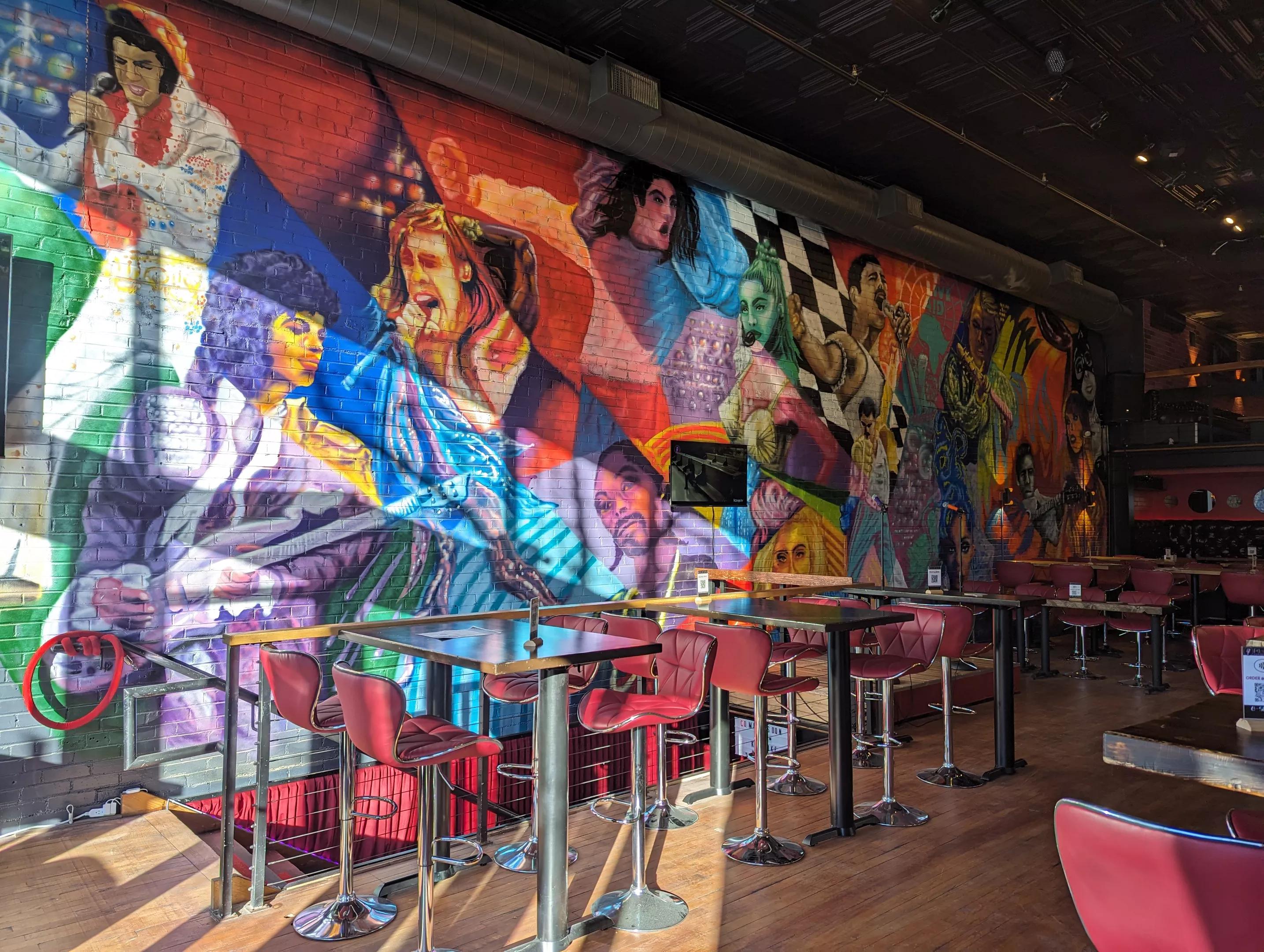 a colorful mural on a wall picturing famous singers