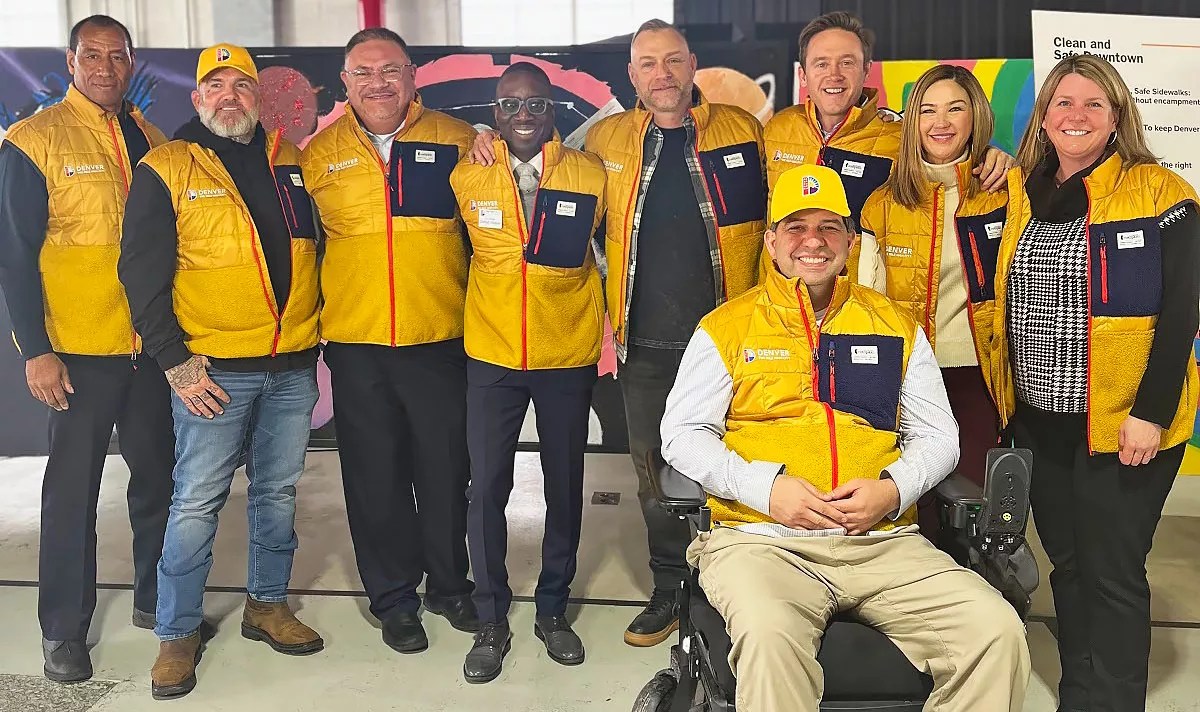 A group of people wearing yellow vests pose for the camera.