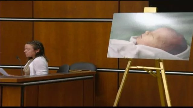 woman testifying in front of baby picture