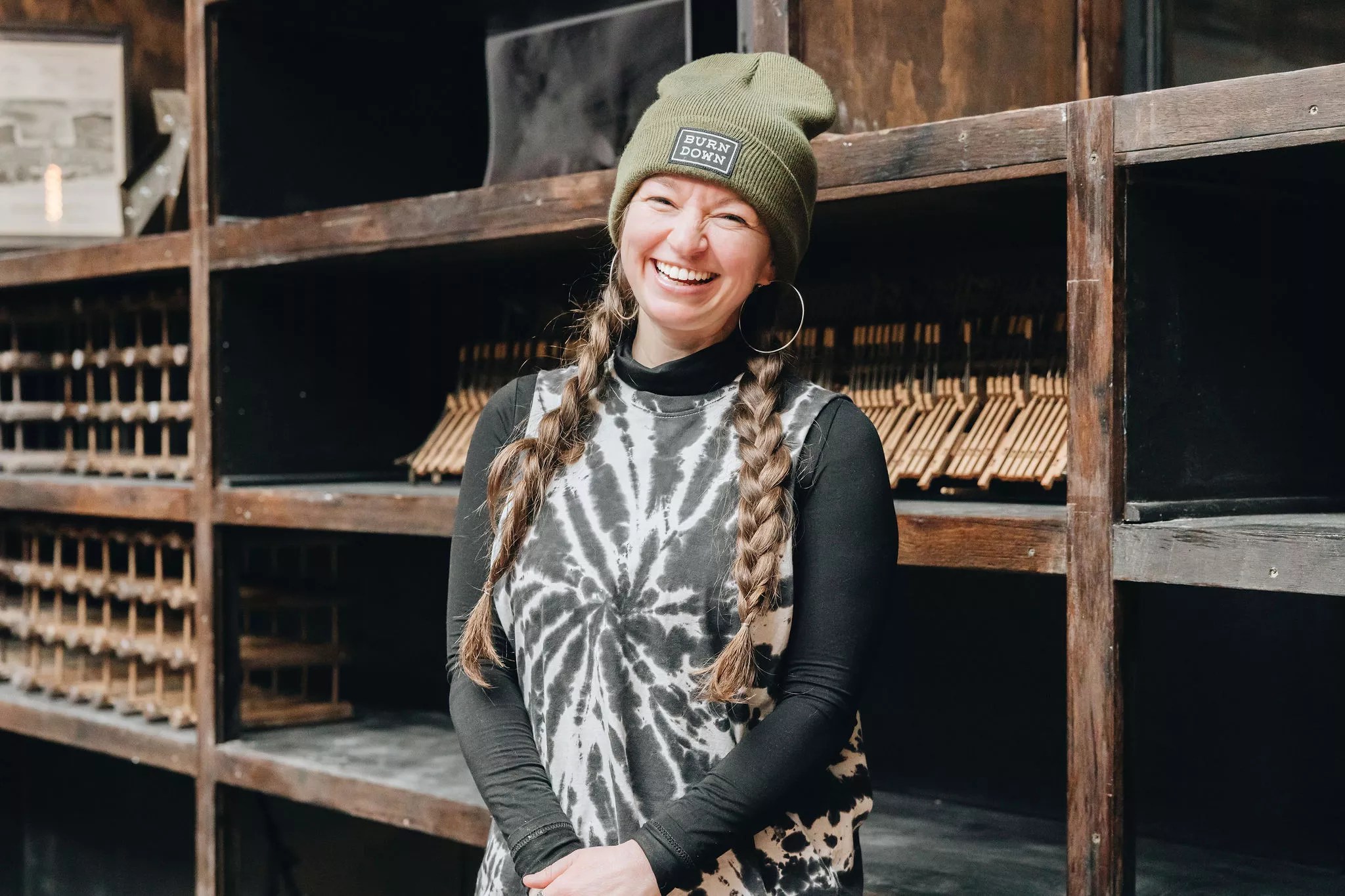 woman smiling in black tie dye and green beanie