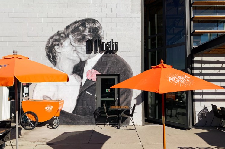 orange umbrellas in front of a mural of two people kissing