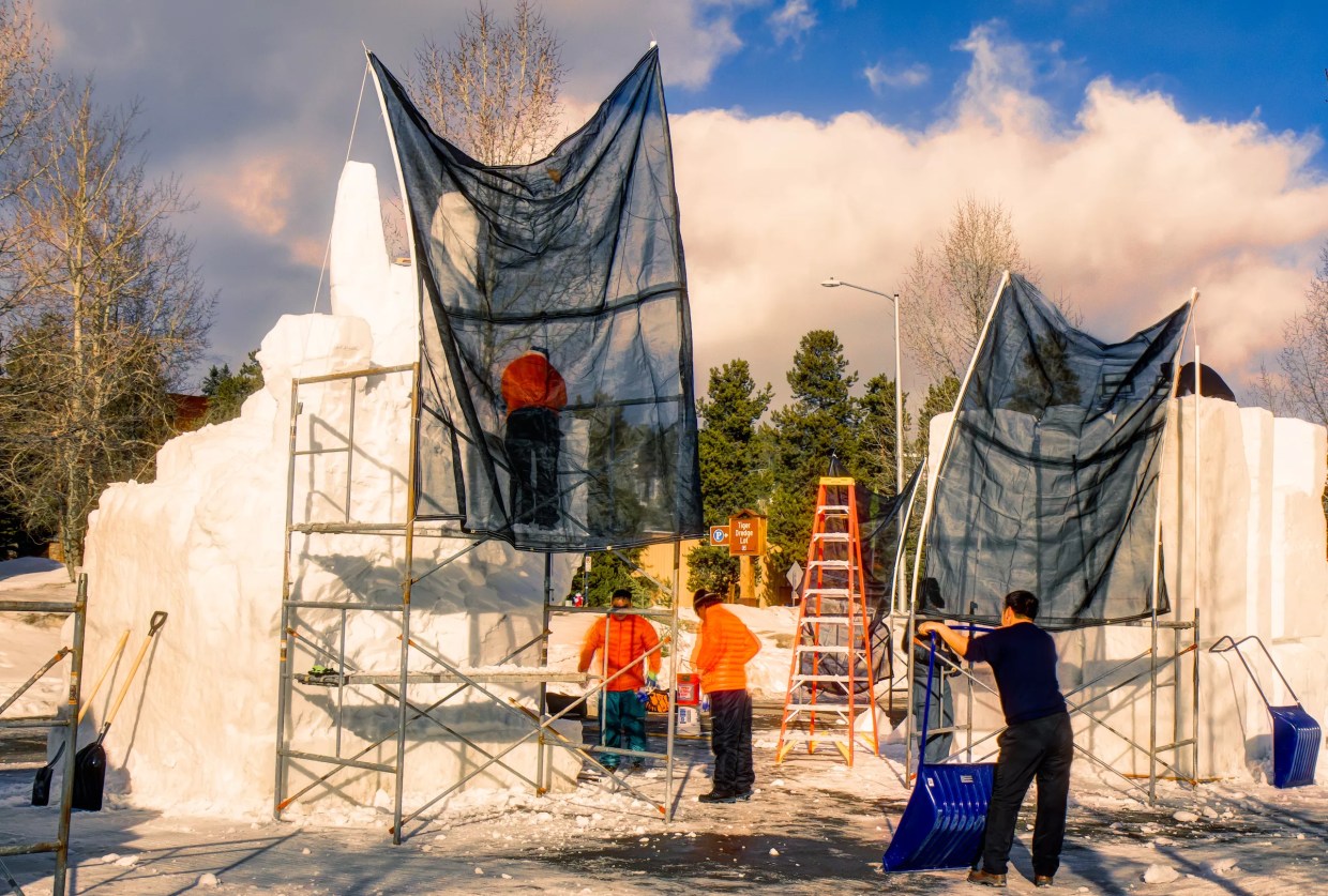 Workers build a snow sculpture with scaffolding in Breckenridge