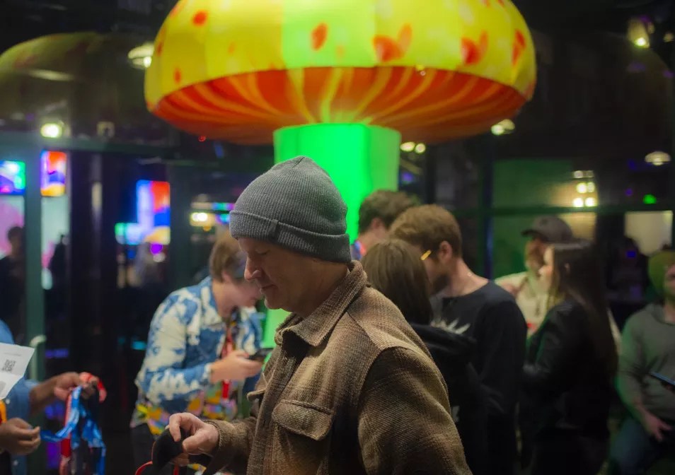 Man in a beanie stands in front of inflatable giant mushroom