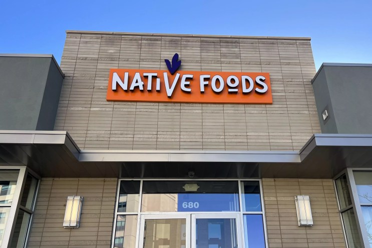 A tan brick building with orange signage reading "Native Foods"