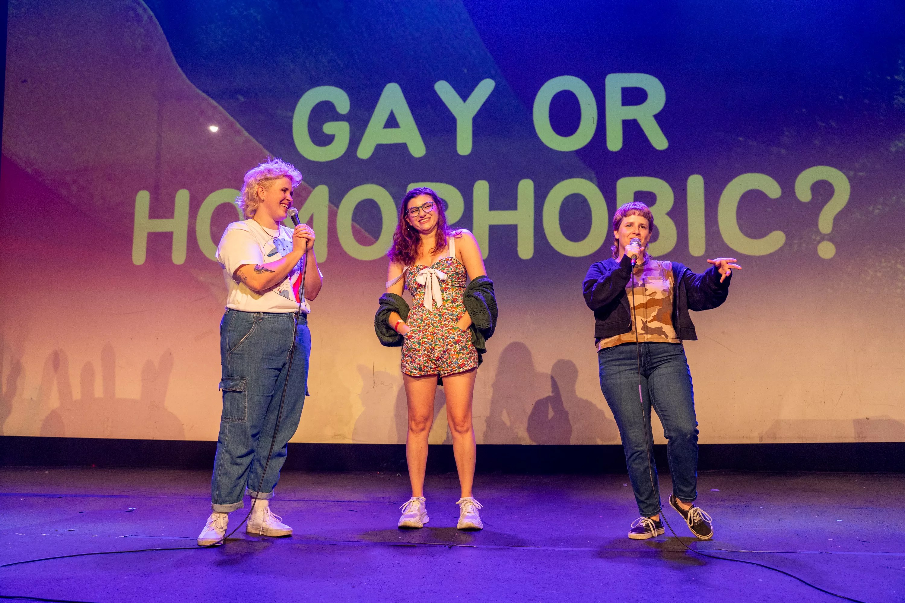 women on stage in front of sign that says gay or homophobic