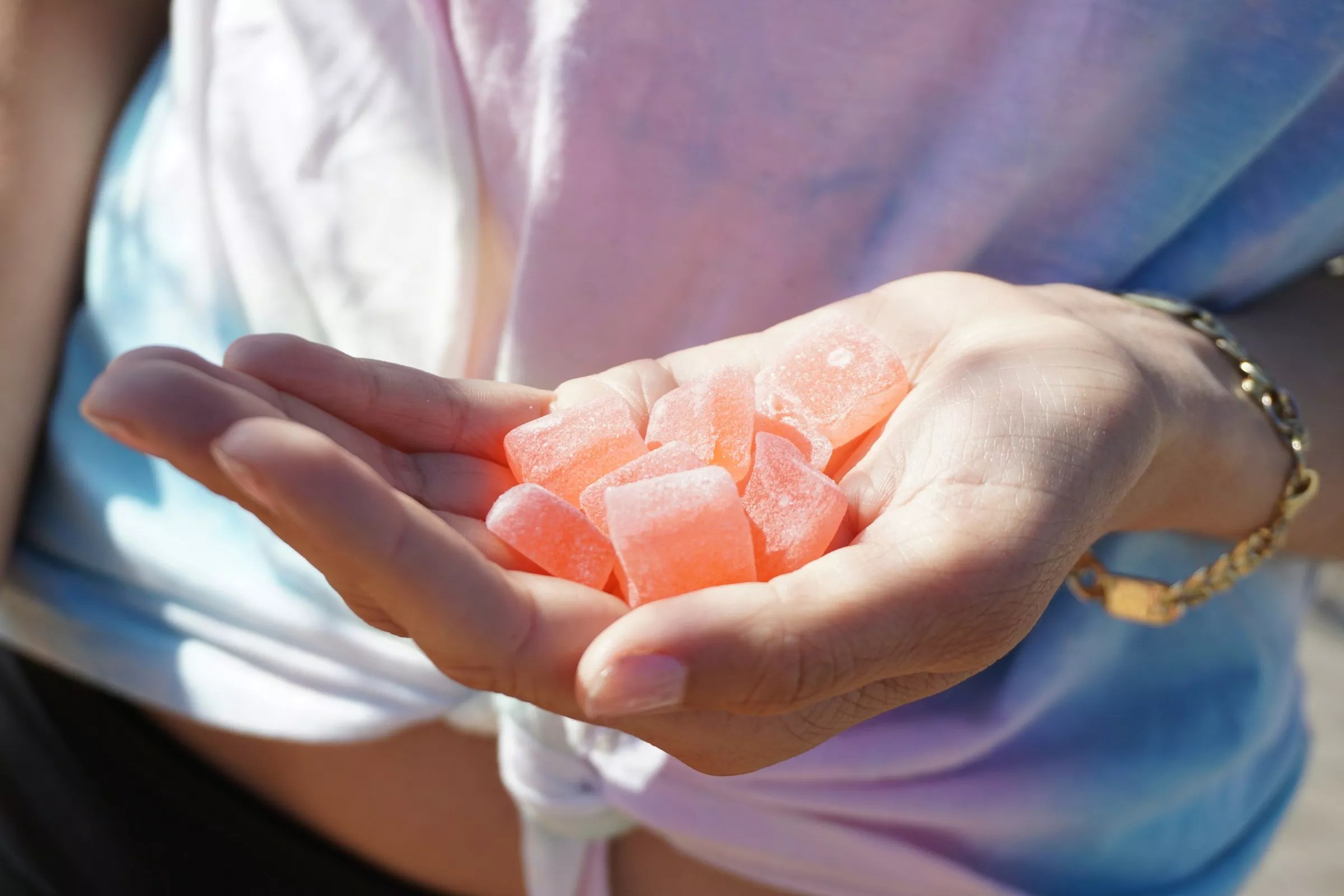 Woman's hand holds orange cannabis gummies