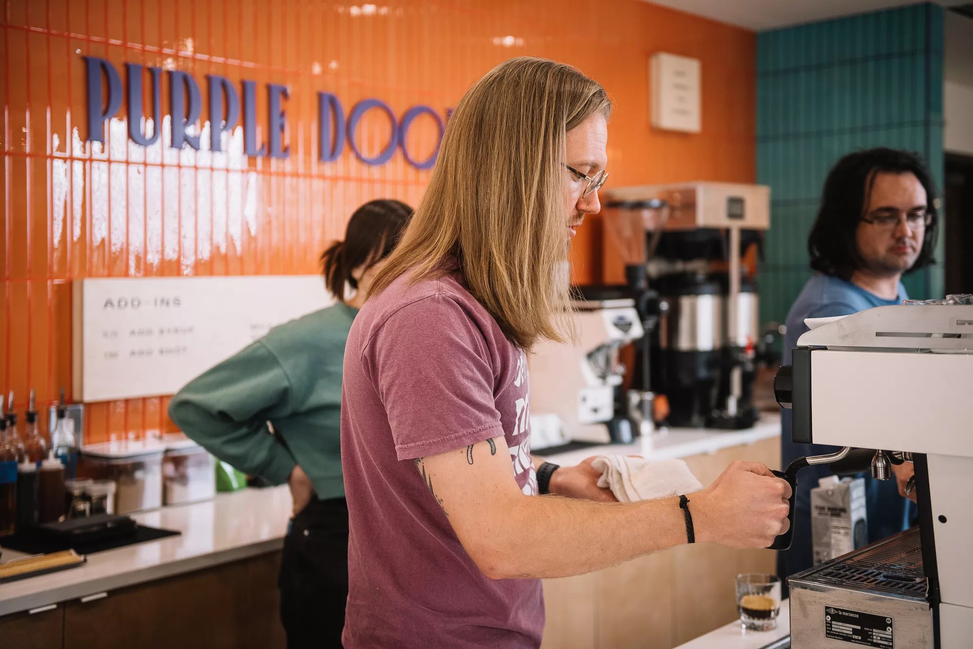a person making coffee behind a counter in a shop