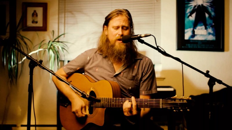 man playing an acoustic guitar at a microphone