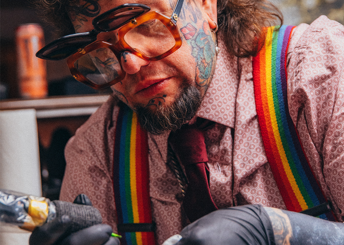 man with tattoos and rainbow suspenders wearing flipshade sunglasses