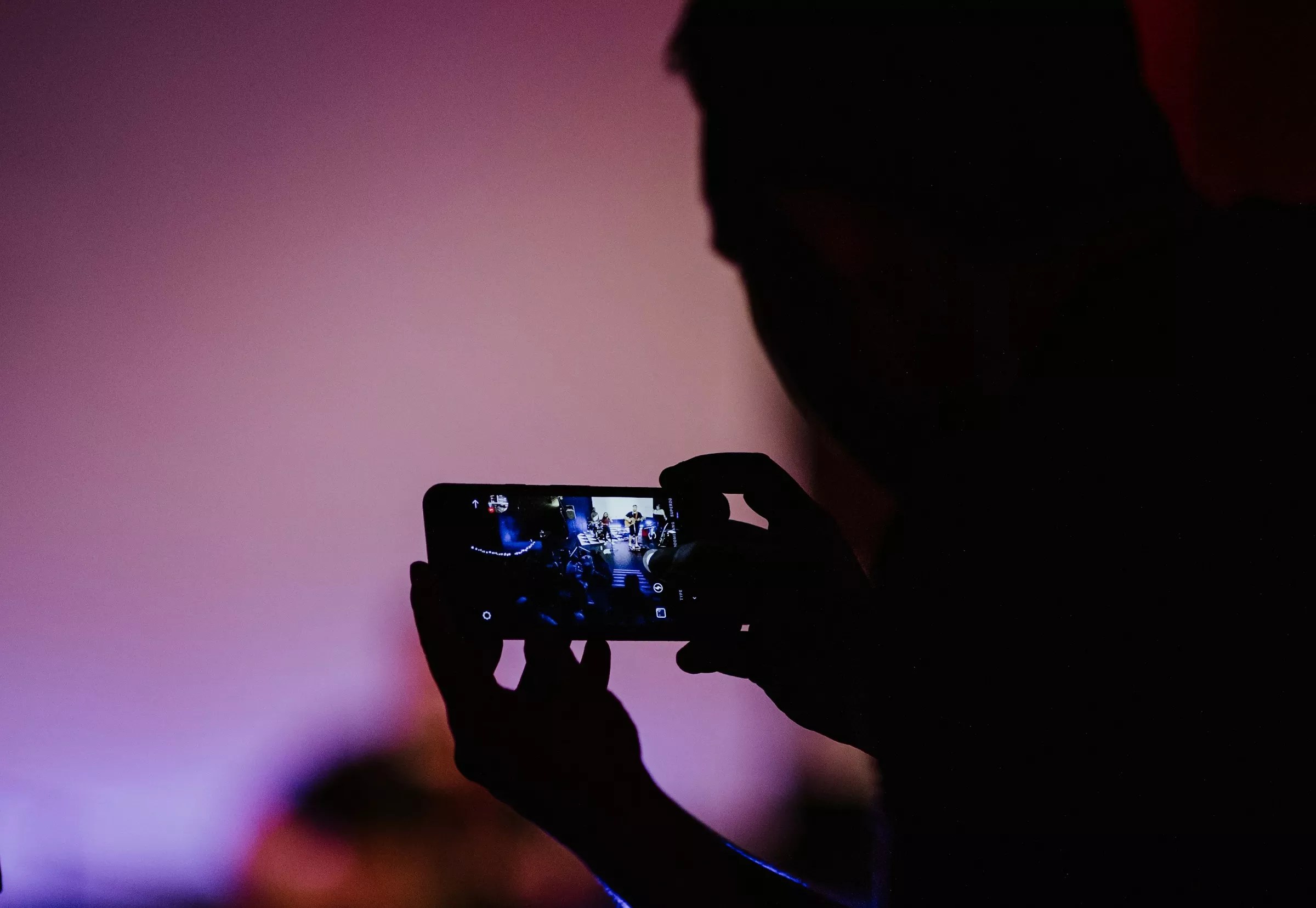 Person records video on phone in shadows