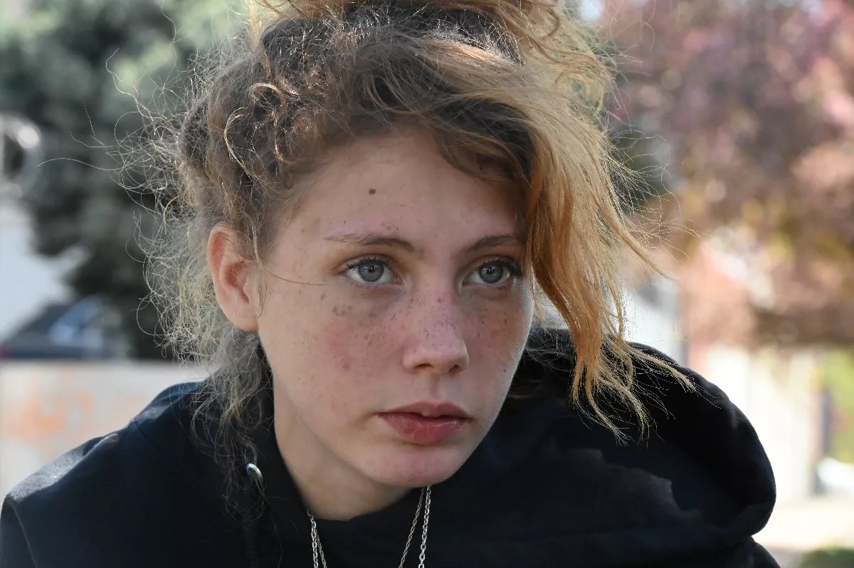 A young homeless woman watches a sweep.