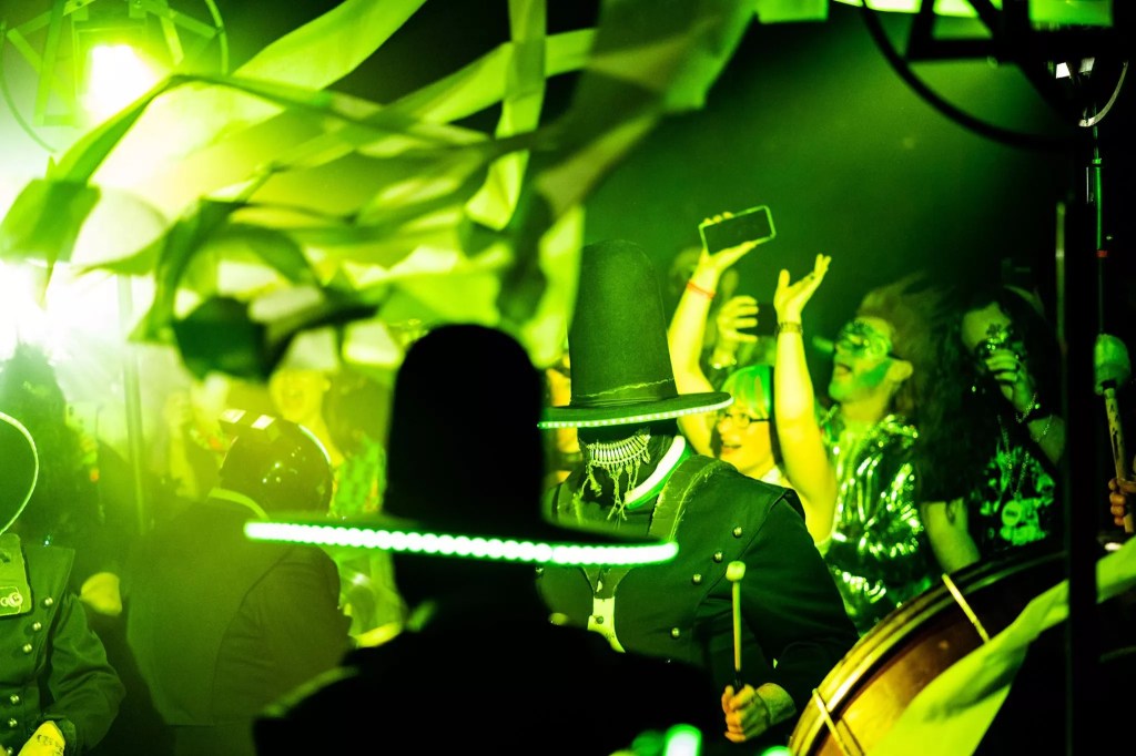 people in masks playing drums with green lighting