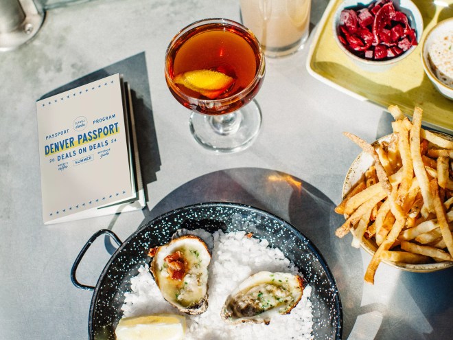a small booklet on a table with oysters, fries and cocktails