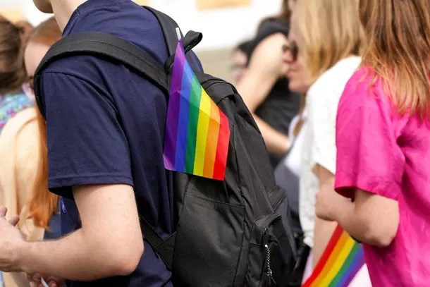 A student wearing a backpack with a small rainbow flag on it, symbolizing LGBTQ pride.