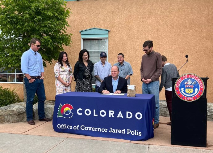 people standing around a table where a man is sitting