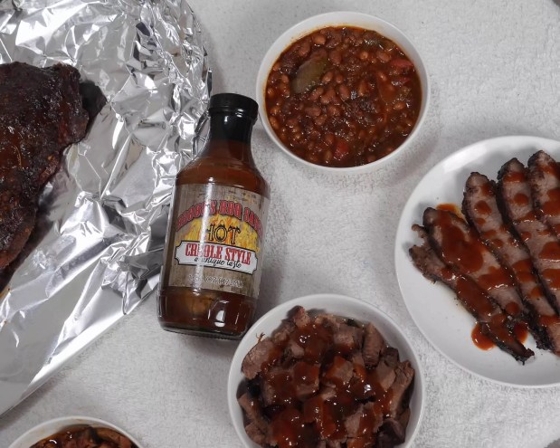 bottle of barbecue sauce with beans and various smoked meats