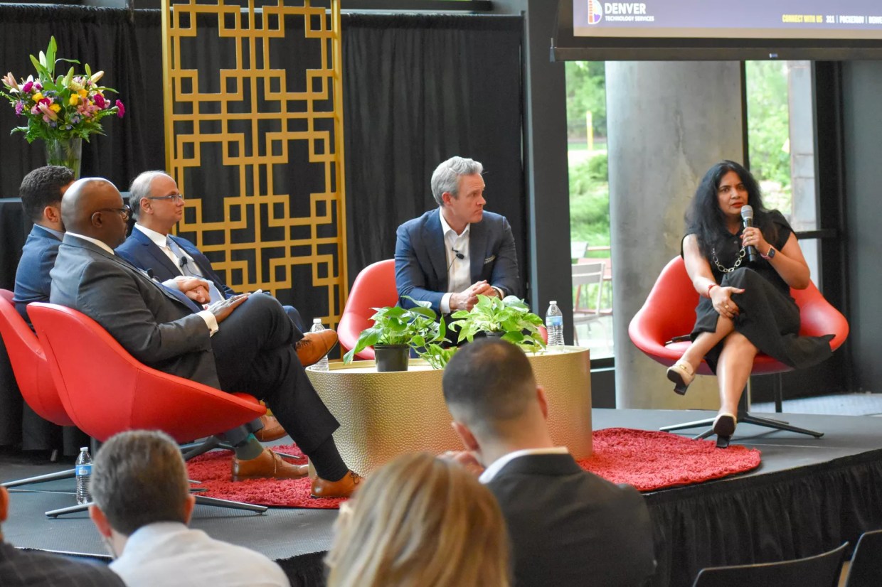 A group of people speaking on a public panel.